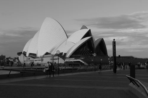 Free Black and white view of Sydney Opera House at dusk with people walking along the promenade. Stock Photo