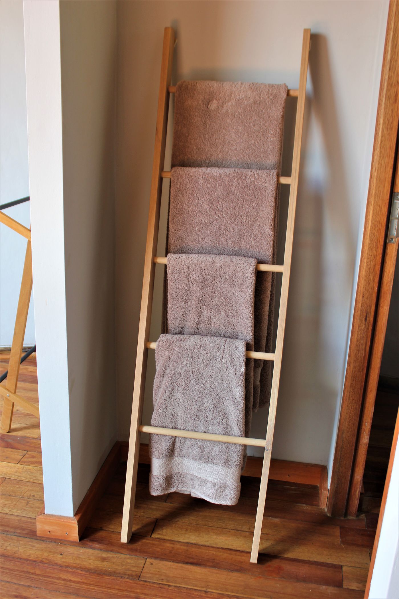 Fresh towels hanging openly on a wooden rack for airflow