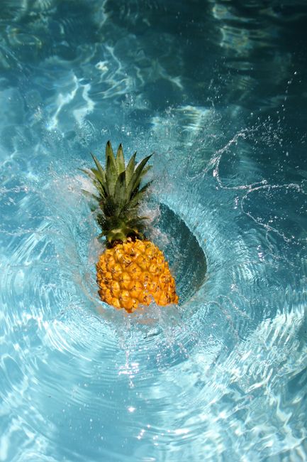 A vibrant pineapple splashes into a refreshing swimming pool, capturing the essence of summer with dynamic motion and bright colors.