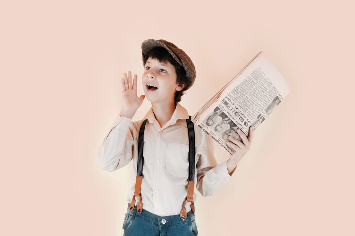 Cheerful Boy Holding Aged Newspaper Against Beige Background Free Stock Photo Cheerful Boy Holding Aged Newspaper Against Beige Background Free Stock Photo