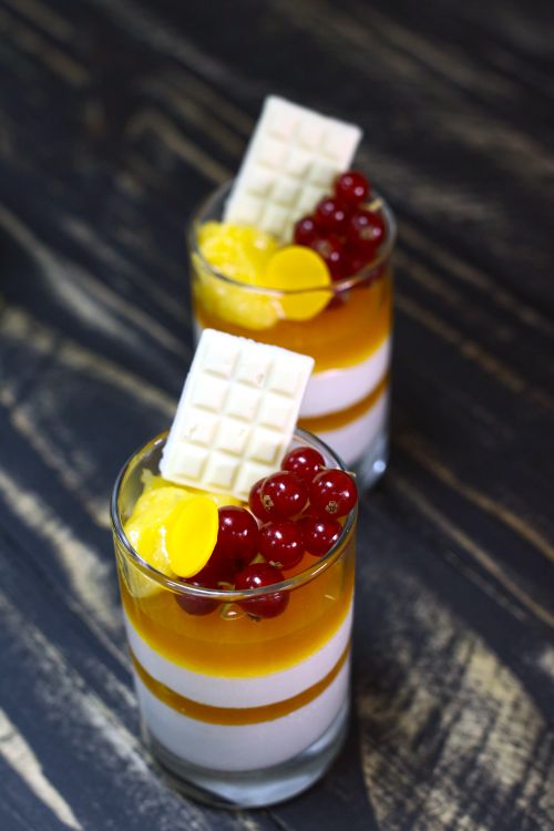 Free Elegant glass desserts with currants, white chocolate, and mango topping. Stock Photo