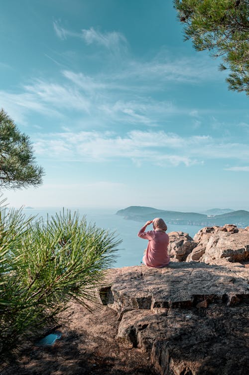 Free A Woman Sitting n Top of the Mountain Stock Photo