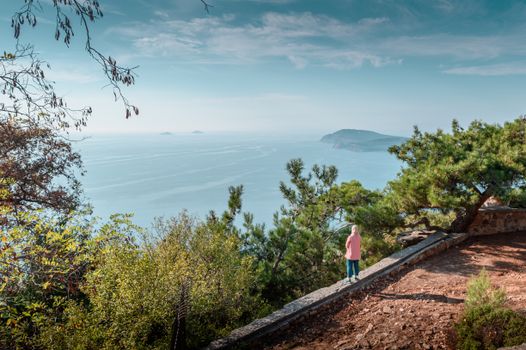 A woman stands on a cliff in Istanbul, overlooking the sea and distant islands.