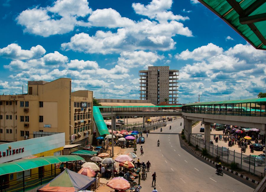 A bustling street scene featuring vibrant colors and lively market under a blue sky with clouds.