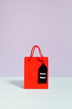 Vibrant red shopping bag with Black Friday tag on pastel backdrop, perfect for promotions.