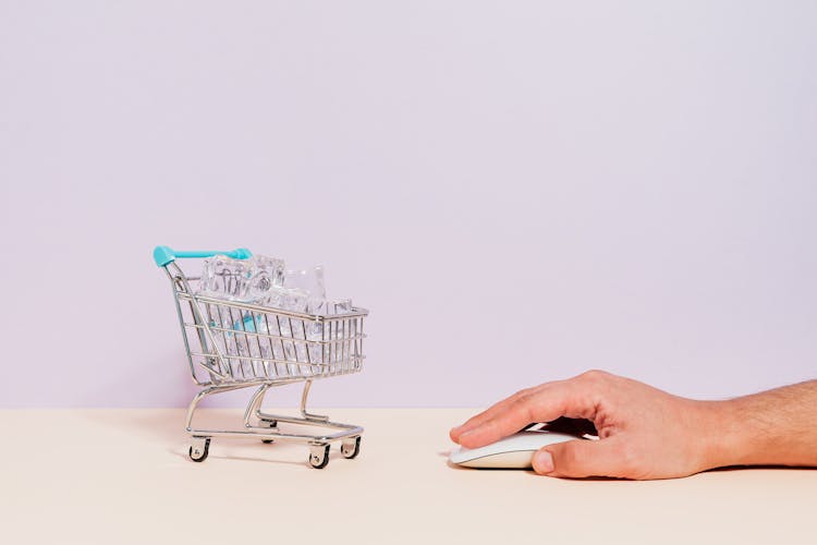 Hand Clicking On Mouse By Miniature Shopping Cart