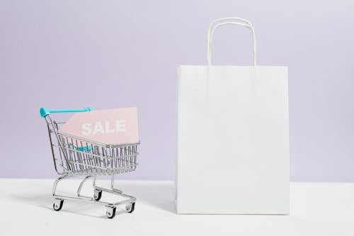 Sale Sign In A Miniature Shopping Cart And Paper Bag