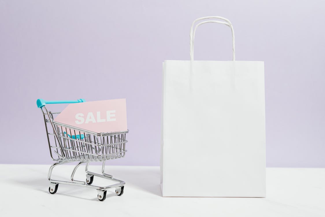 Free Sale Sign In A Miniature Shopping Cart And Paper Bag Stock Photo