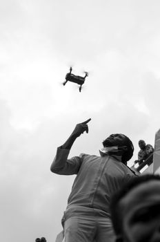 Black and white image of a man pointing at a drone during a protest.