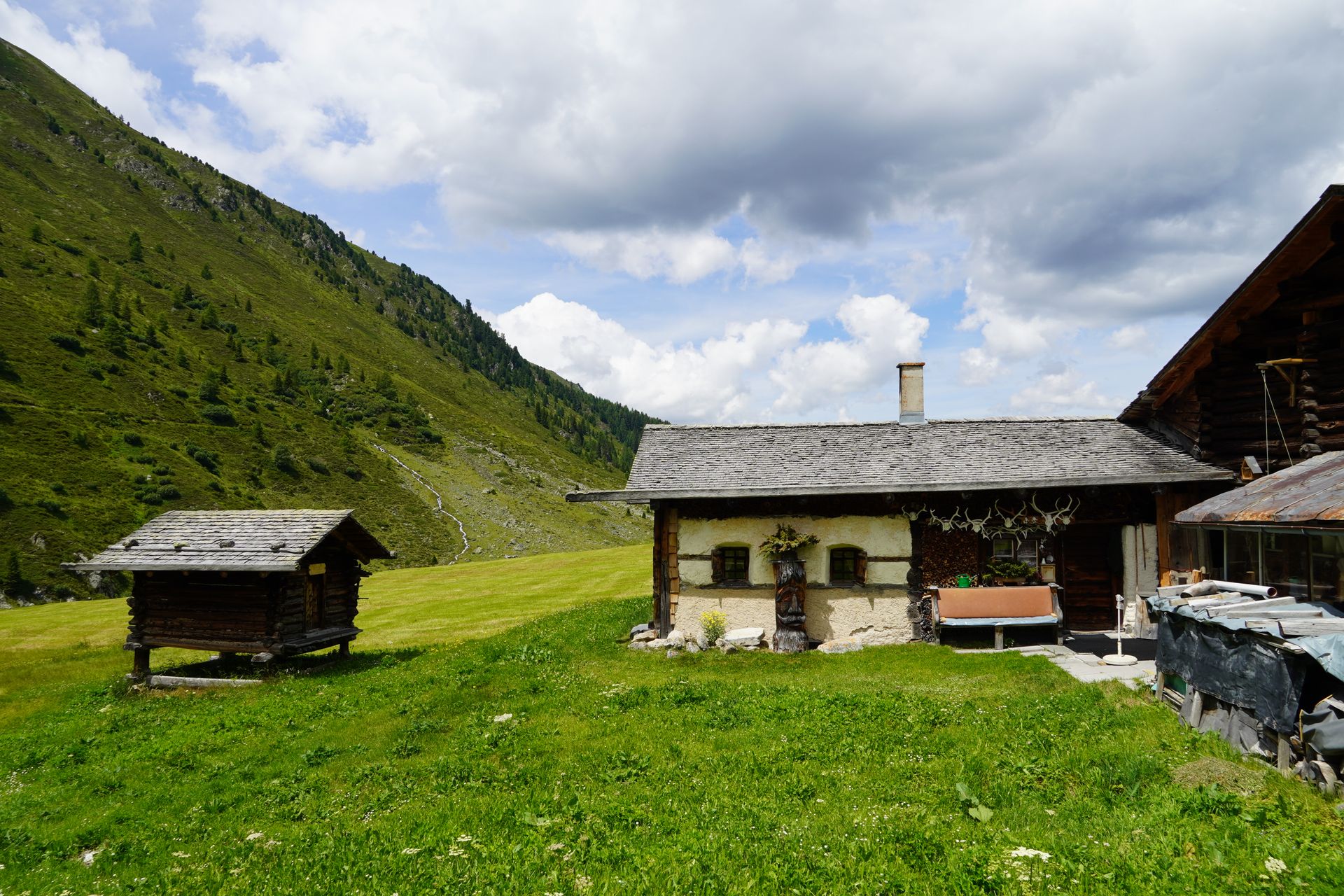 Rustic Swiss chalet in Davos surrounded by lush greenery and mountains under a cloudy sky.