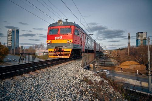 Free A red train crosses an elevated railroad bridge in a city during day time, capturing urban transit. Stock Photo