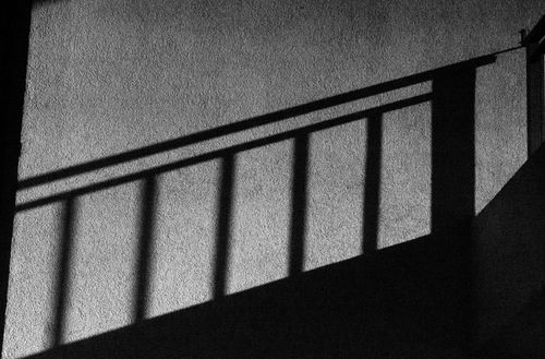 Free Artistic black and white abstract shadow of railings cast on a textured wall. Stock Photo