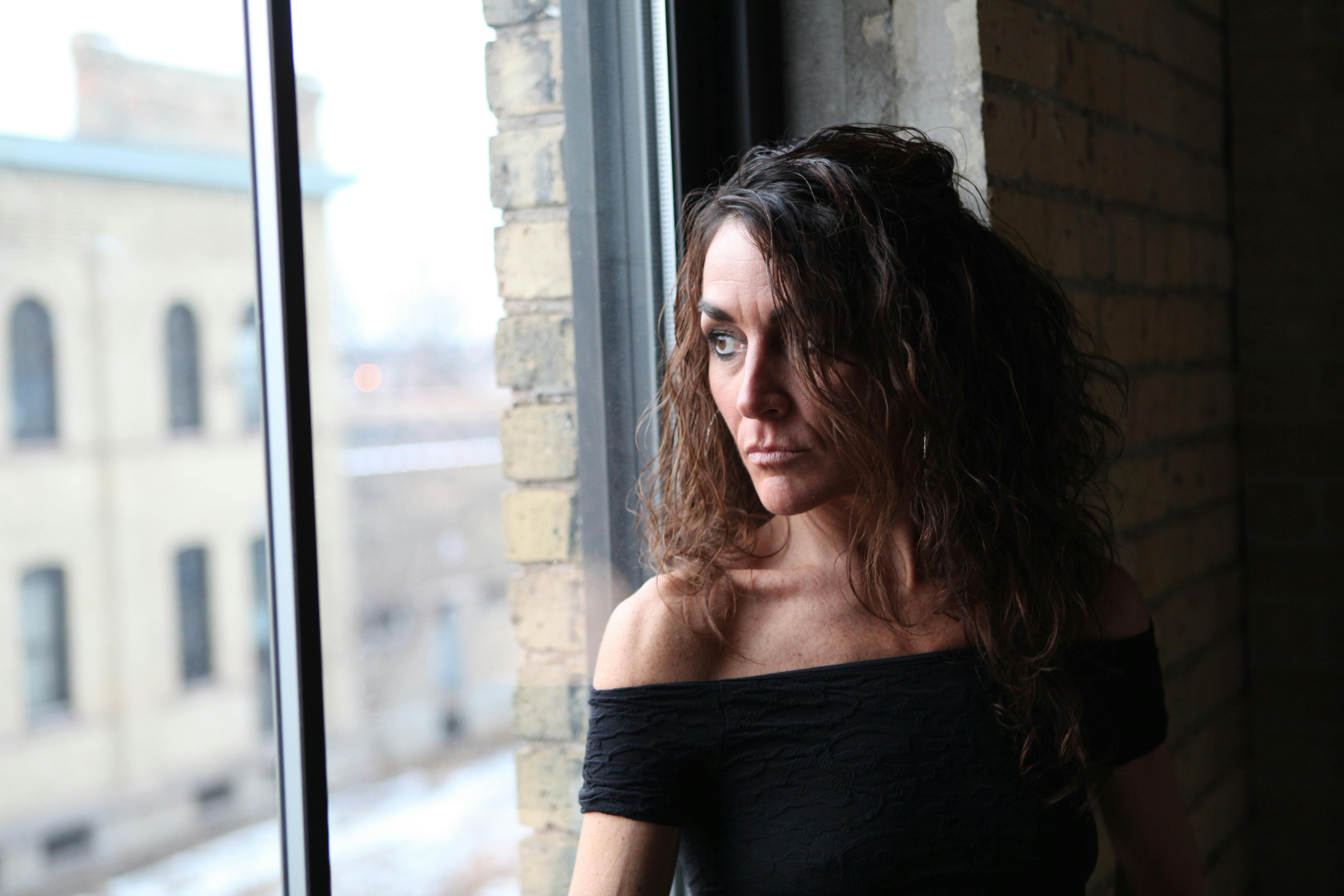 Portrait of a thoughtful woman gazing out a window in Minneapolis, capturing a serene and introspective moment.