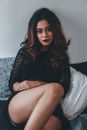 Woman in Black Long Sleeve Shirt Sitting on White Bed