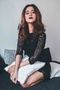 Woman in Black and White Long Sleeve Shirt Sitting on White Bed