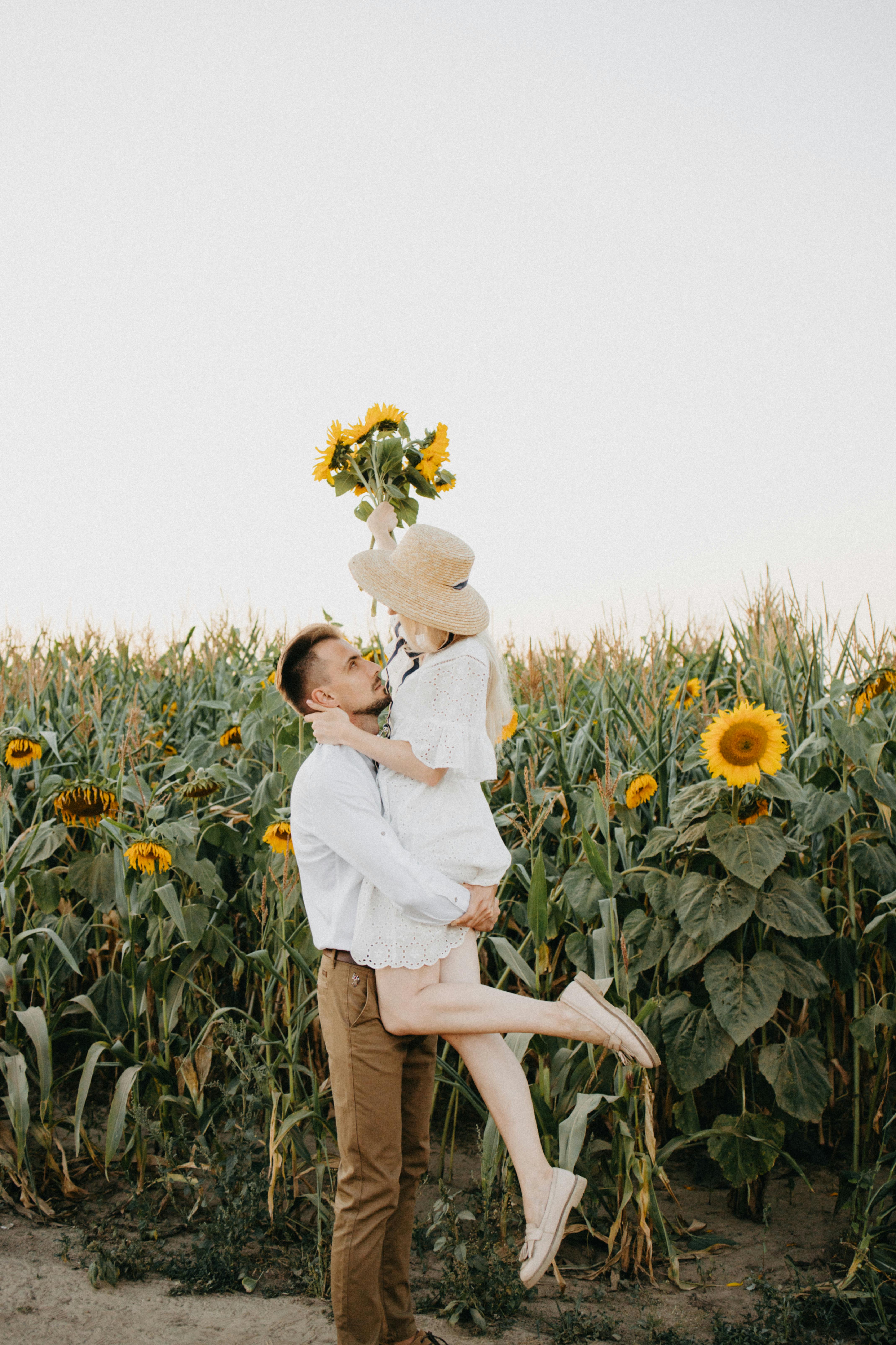 在一个明亮的夏日里，一对快乐的夫妇在向日葵地里拥抱