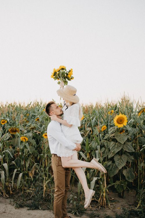 Free A joyful couple embracing in a sunflower field during a bright summer day. Stock Photo