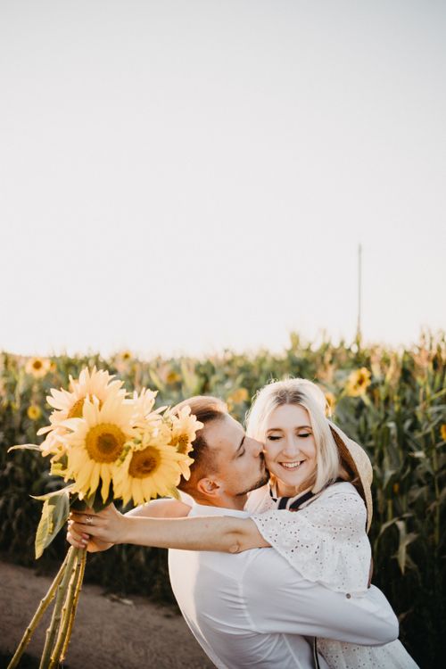 Free Happy couple hugs with sunflowers in a scenic field, capturing a moment of love and joy. Stock Photo