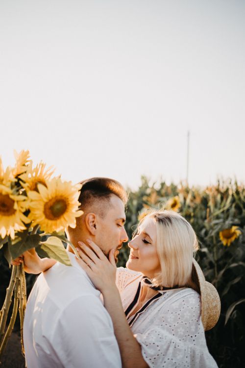 Free A loving couple embraces in a sunflower field during sunset, evoking romance and warmth. Stock Photo