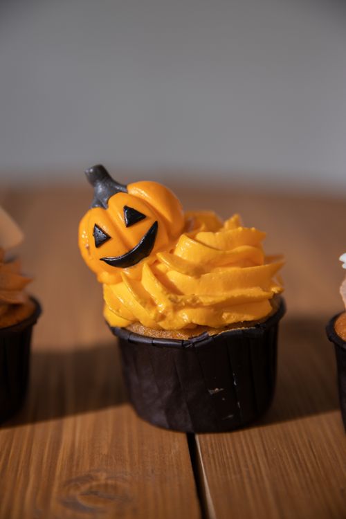 Free Delicious pumpkin-themed cupcake with vibrant orange frosting, perfect for Halloween celebrations. Stock Photo