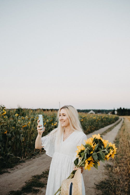 A Woman in White Dress Collecting Sunflowers