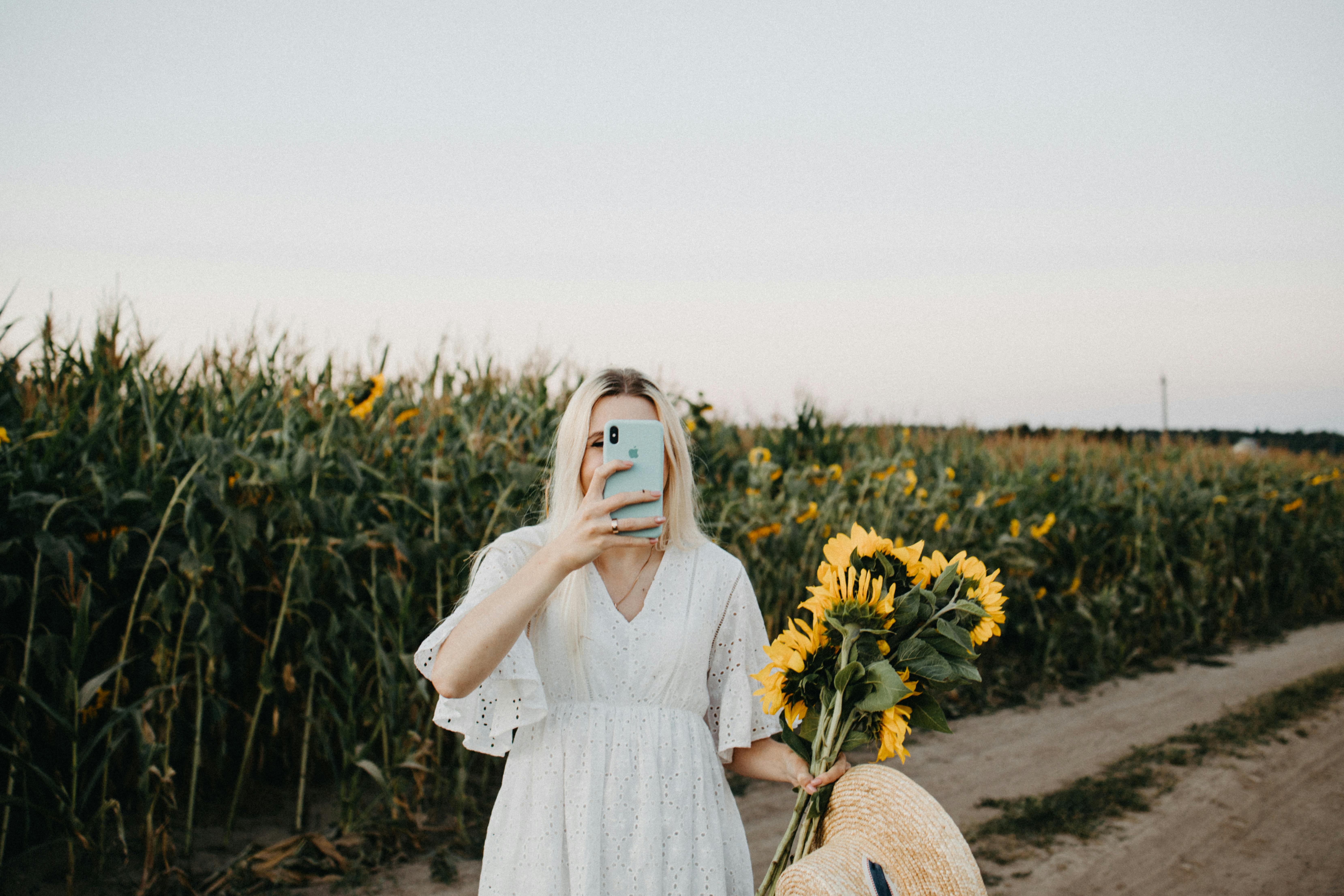 woman in white dress standing on yellow flower field