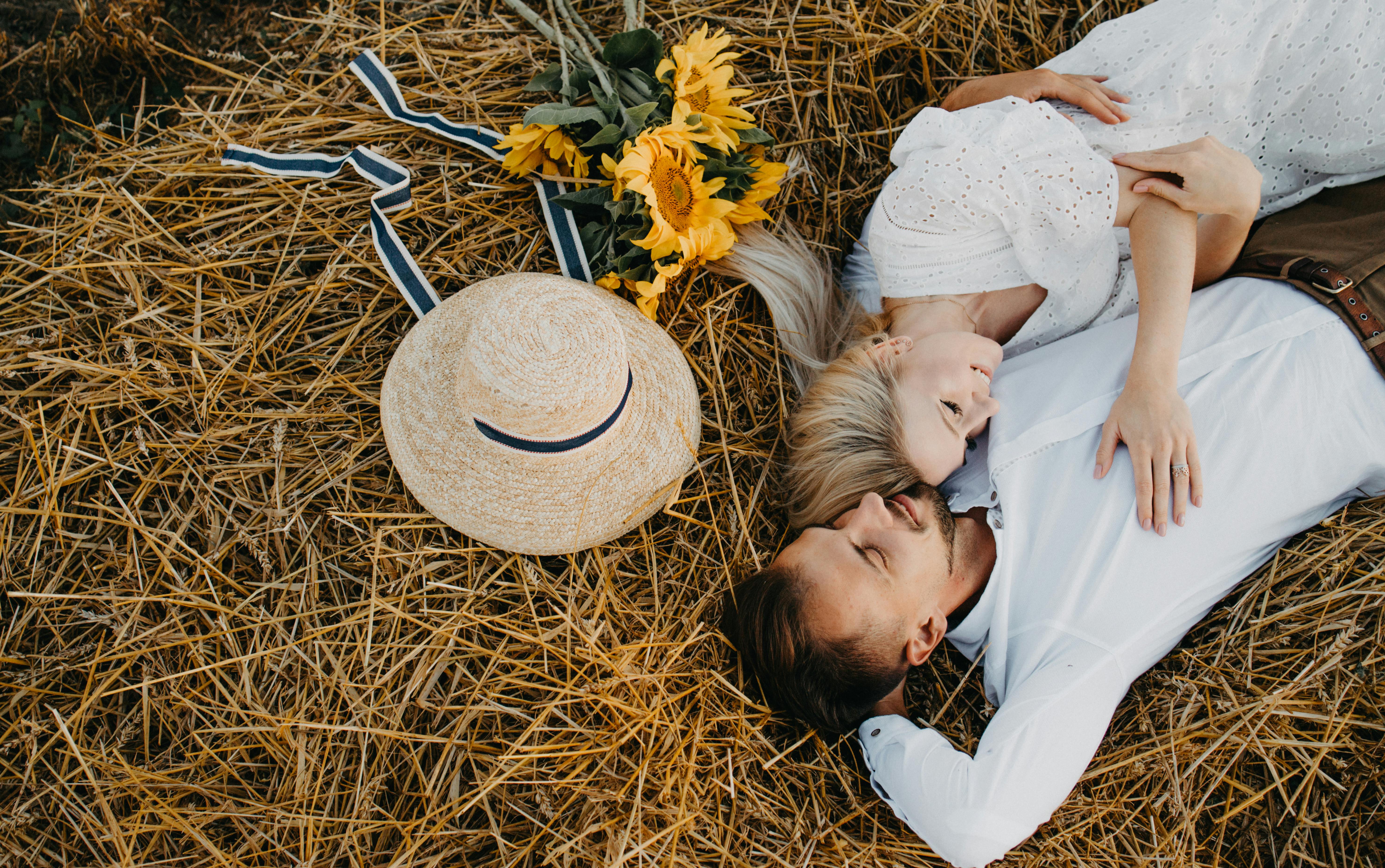 a couple lying down on haystack