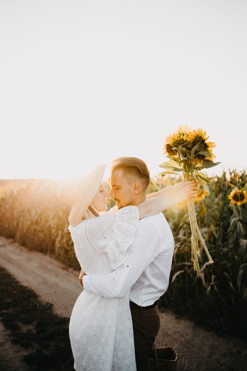 Free Young couple kissing in a sunny sunflower field, conveying love and romance. Stock Photo