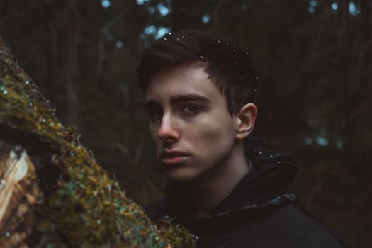 Moody portrait of a young man in a forest setting, capturing an enigmatic and introspective vibe.
