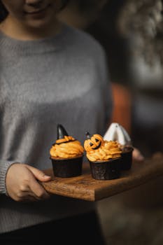 Halloween-themed cupcakes with decorative frosting on a wooden tray, perfect for fall celebrations.