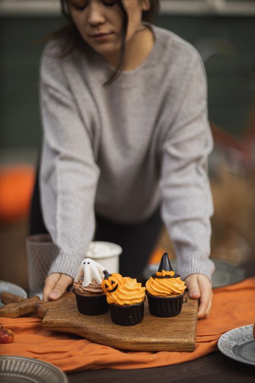 Free Halloween-themed cupcakes with ghost and witch toppers on a serving board. Stock Photo