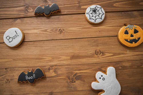 Free Festive Halloween cookies with ghost, pumpkin, and bat decorations on wooden surface. Stock Photo