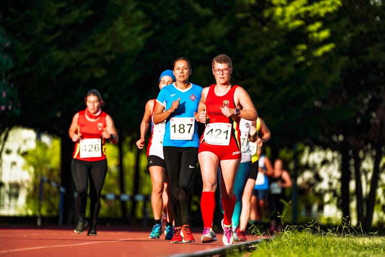 Fit Female Athletes Running On Race Track During Competition