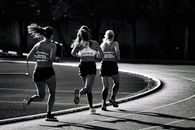 Faceless professional athletes running on race track in stadium
