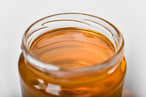 Free Close-up of a jar filled with golden honey, emphasizing its smooth texture and shimmering hue. Stock Photo