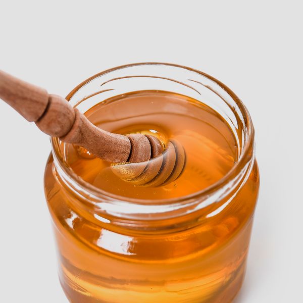 Glass jar of honey with a wooden dipper