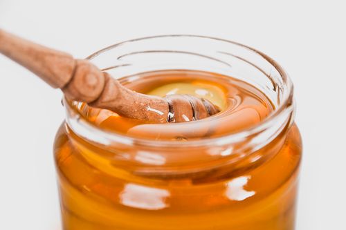 Free A detailed close-up of a wooden honey dipper in a jar filled with golden honey. Stock Photo