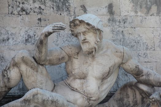 Close-up of a muscular mythological marble sculpture with a classic renaissance style, outdoors.