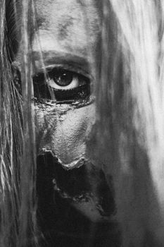 Black and white headshot of serious scary female with spooky greasepaint and long hair covering half face looking at camera