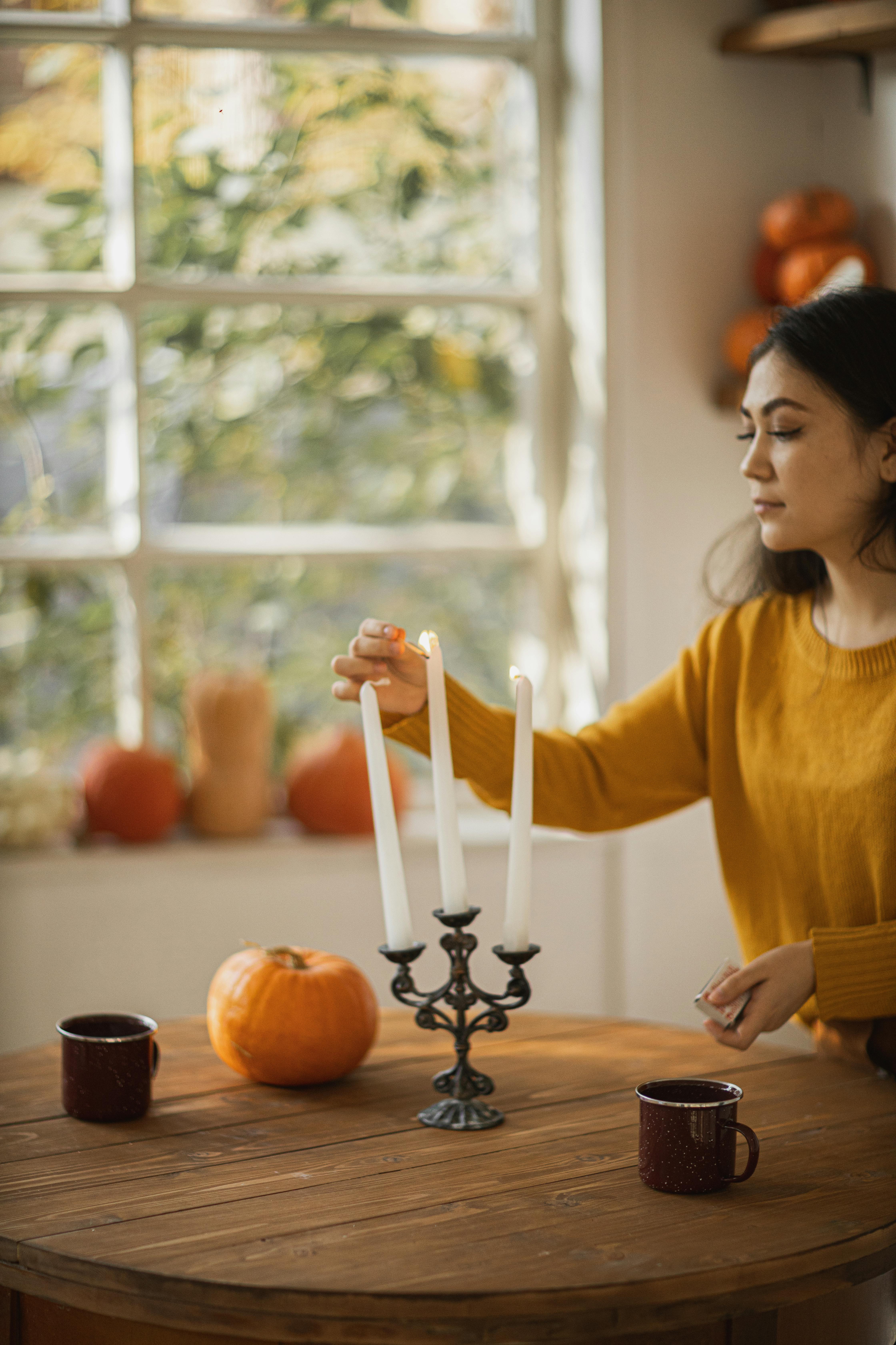 woman in yellow long sleeve shirt lighting a candle