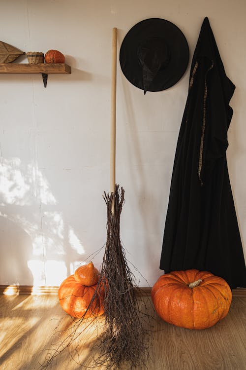 Free Orange Pumpkin Beside Black Witch Costume and a Broom Stock Photo