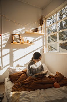 Woman reading in a sunlit bedroom, surrounded by autumn decor and pumpkins.