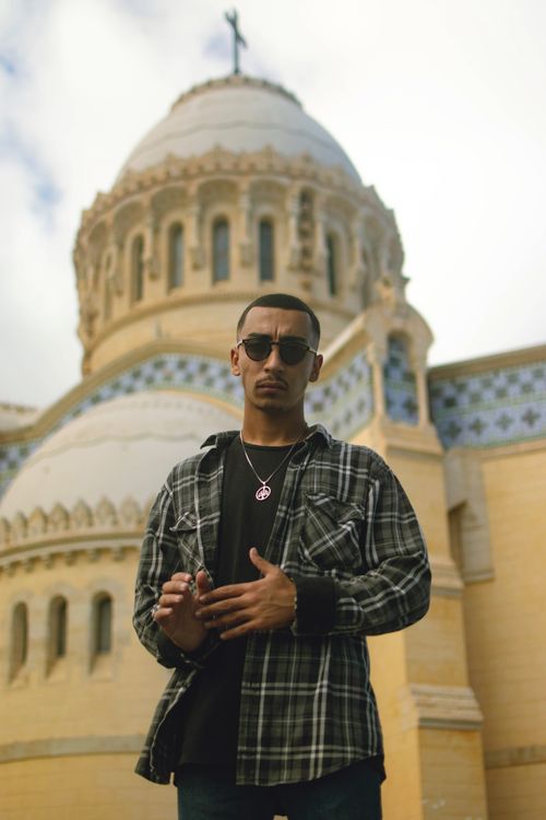 Free Man in sunglasses standing before an iconic Algerian dome building. Stock Photo