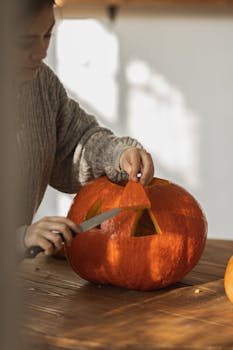 A woman carves a pumpkin indoors for Halloween on a cozy fall afternoon, capturing seasonal creativity.