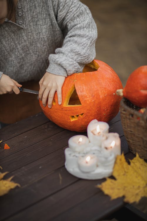 Person in Gray Long Sleeve Shirt Carving Jack O Lantern