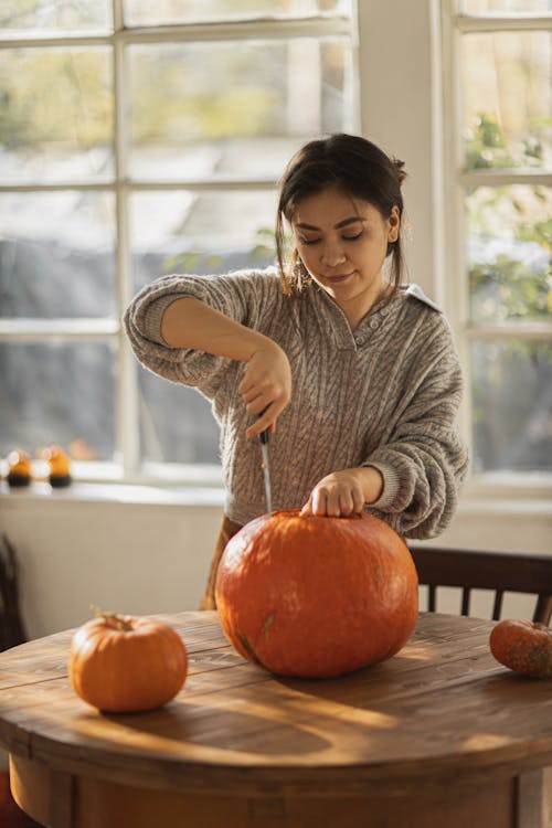 Woman in Gray Long Sleeve Shirt Holding Pumpkin