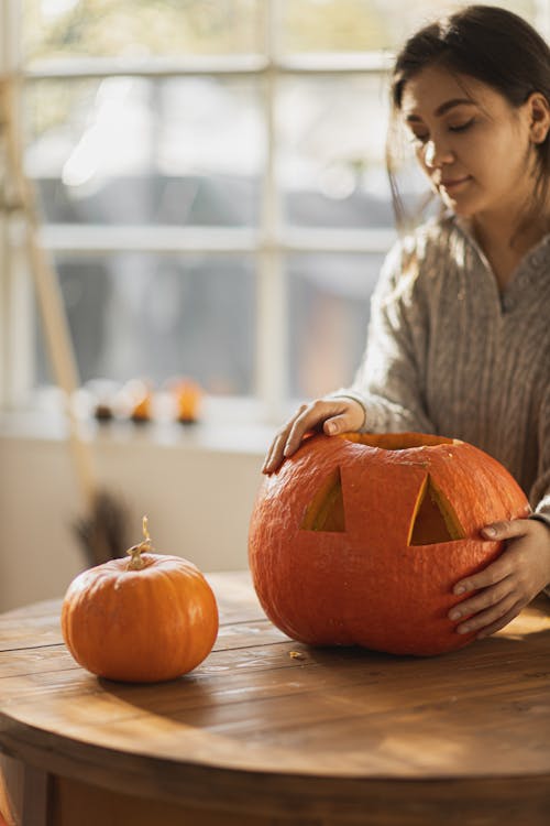 Woman in Gray Long Sleeve Shirt Holding Pumpkin