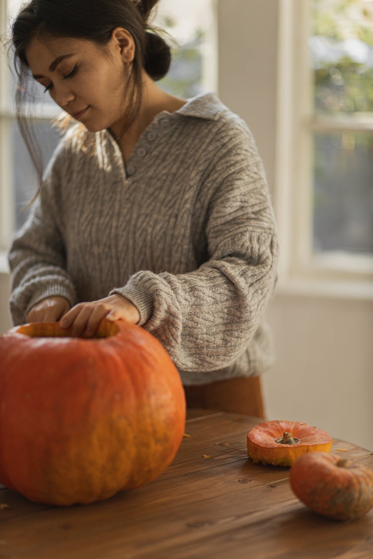 Woman In Gray Sweater Holding A Big Pumpkin