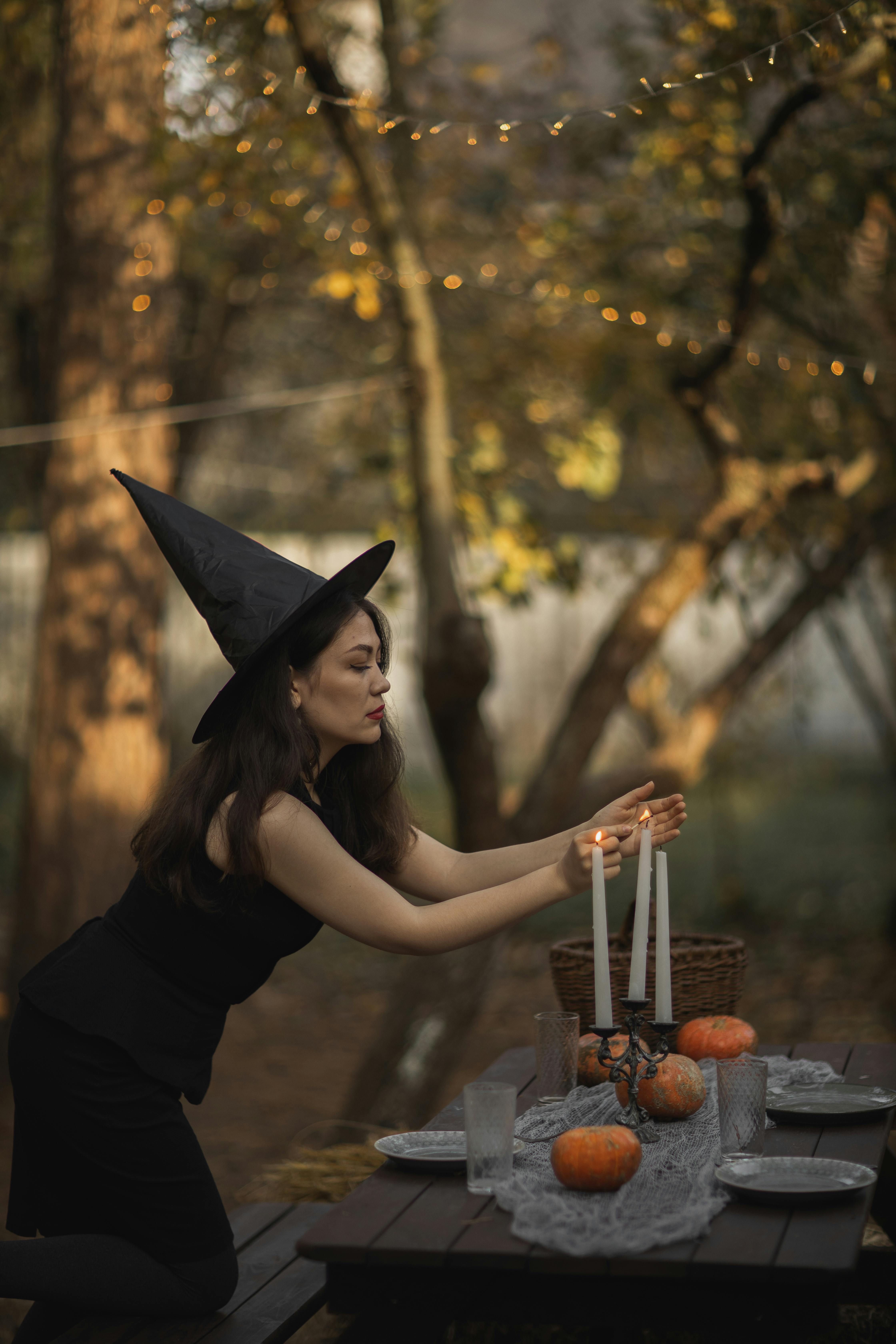 woman in black dress and black hat lighting the candles