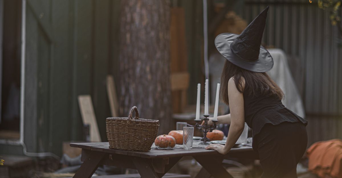 Une sorcière prépare une table avec des bougies et des citrouilles